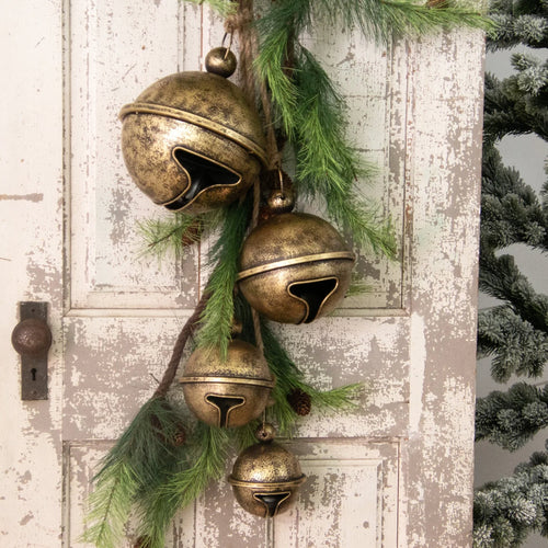 Antique gold round metal jungle bells on jute hung on a chippy rustic door