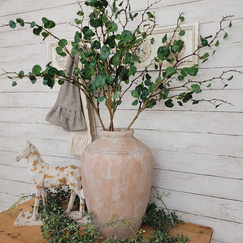 Artificial begonia leaf branch centerpiece in an aged terracotta pot.