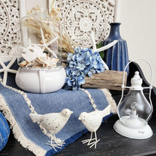 Load image into Gallery viewer, The coastal cottage side table vignette has a seashell filled terrarium, chippy bird figurines, and an LED steeple lantern.
