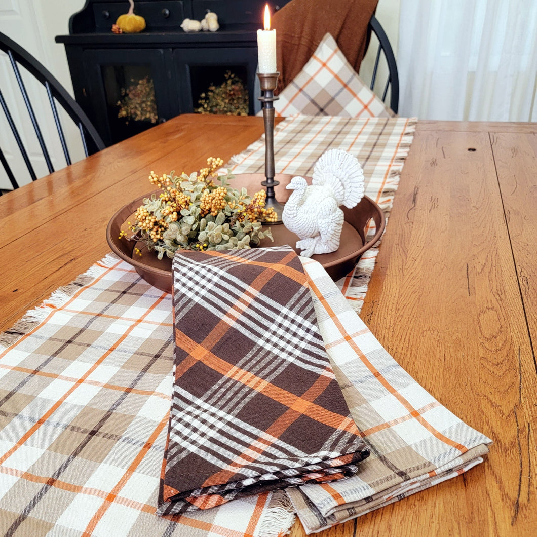 Autumn centerpiece with a copper tray, sage half orb, and plaid table runner and tea towels.