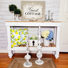 Load image into Gallery viewer, French guest cottage wall decor and console table styling with chippy finials, vintage glass taper candle holders, blue gingham pillow and boxwood spheres
