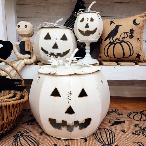 Rustic white metal jack o' lanterns with lids and a burlap raven pillow.