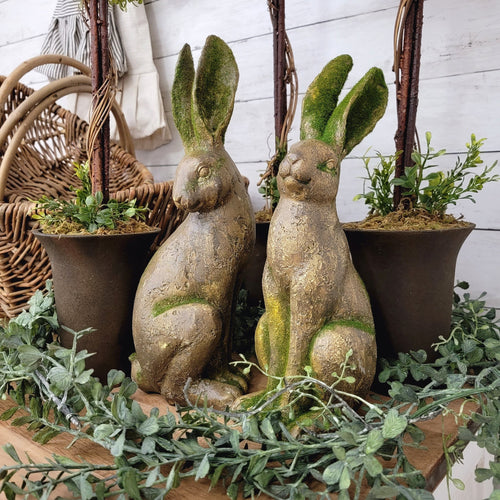 Mossy rabbit figurines surrounded with faux boxwood greenery. 