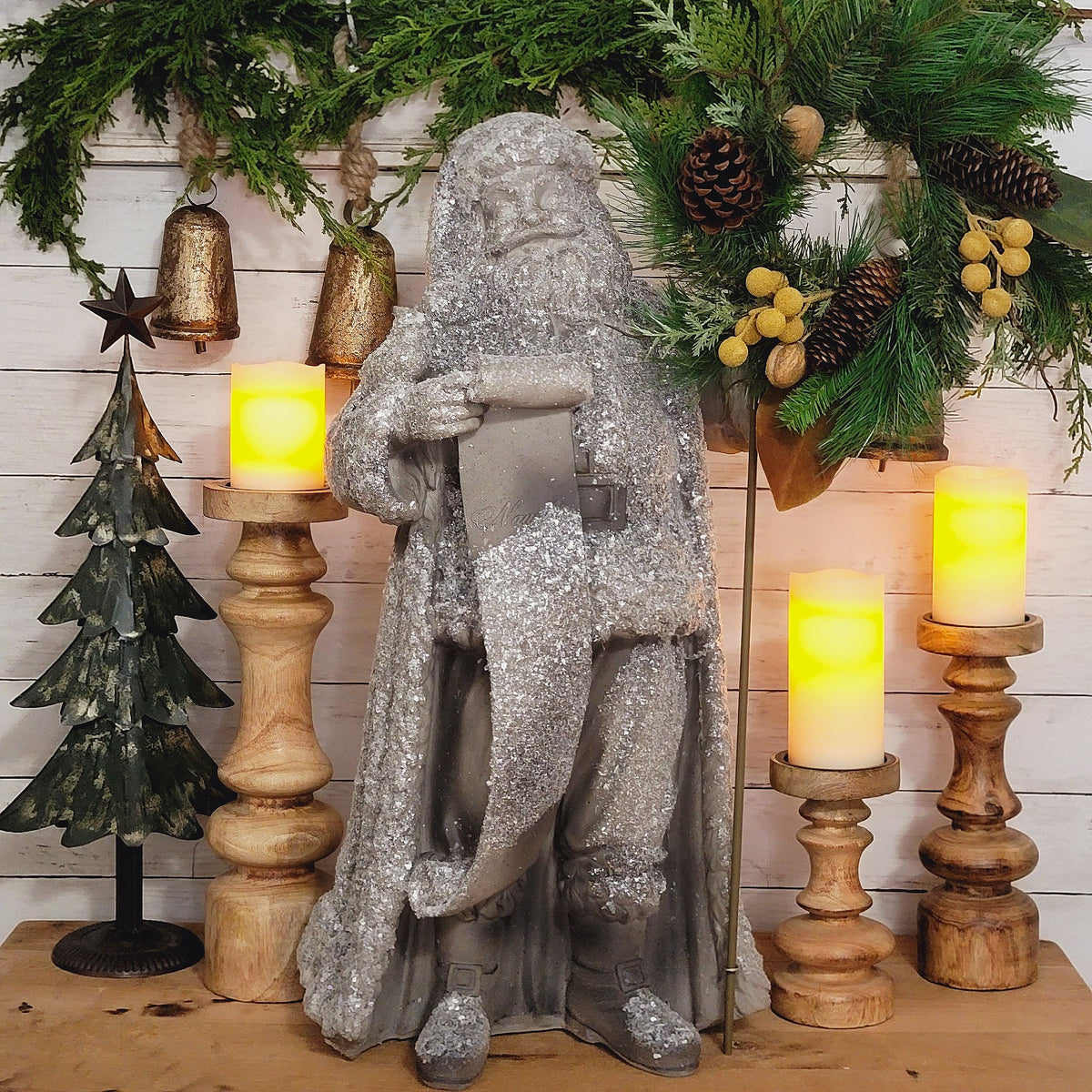 Glitter frosted Santa statue holding a woodland wreath.
