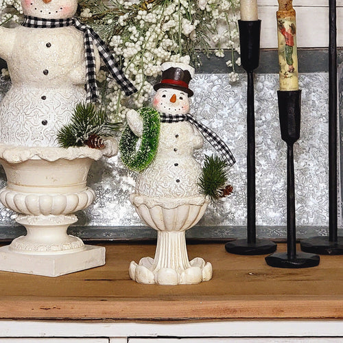 Vintage inspired shabby chic snowman figurine on an ornate pedestal.