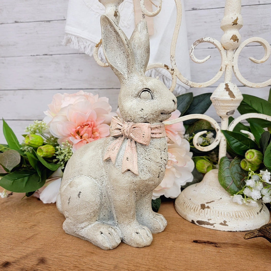 Vintage inspired chippy white sitting rabbit figurine with a light pink bow.