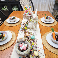 Load image into Gallery viewer, Spring Easter tablescape with a pastel egg and twig garland surrounded by a large glass cloche filled with eggs on an ornate column pedestal, a cottage bunny statue, and a resin birds best.
