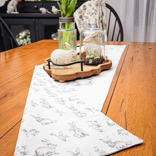 Easter tabvlescape with a neutral rabbit and wildflowers reversible beige table runner with an ornate wood tray centerpiece.