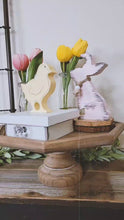 Load and play video in Gallery viewer, Video of an Entryway Easter Table Display with Metal Garden Gate Wall Decor Pink and Lavender Floral Wreath Wood Cutout tulips Distressed Rustic Bunny
