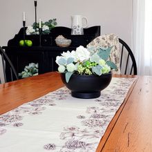 Load image into Gallery viewer, Classic black and white tablescape on a wood farnouse kitchen table featuring sketch like floral table runner with black and white stripe on the reverse. Black sideboard cabinet shelf with iron taper candle holders, cement like resin bird nest, bright green pears, artificial greenery, and a white ceramic pitcher.
