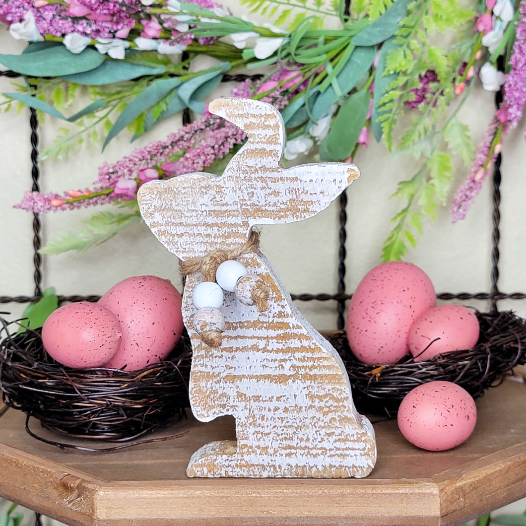 Distressed wood bunny cutout with faux pink Easter eggs in bird nests