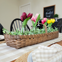 Load image into Gallery viewer, Spring or Easter centerpiece Assorted tulips in milk bottle glass vases set inside a rectangle brown chipwood weaved basket with sage green faux garland set on a tan and white buffalo plaid table runner
