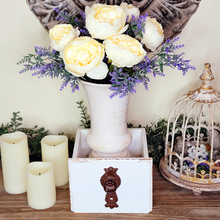Load image into Gallery viewer, Side table display with flameless pillar candles faux lavender and white peonies in an off-white ceramic vase setting in a wood antique style drawer next to an ornate birdcage cloche 
