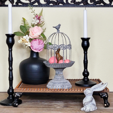 Load image into Gallery viewer, matte black ceramic vase with pink and purple artificial peonies black metal taper candlestick holders on a beaded wood tray metal birdcage cloche pink easter eggs faux chocolate bunny and long earred cast iron tabletop rabbit
