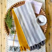 Load image into Gallery viewer, Farmhouse kitchen with round wood beaded tray and gray plaid, stripe, and mustard yellow tea towels.

