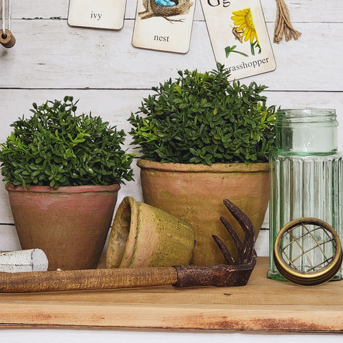 Aged moss terracotta pots and a vintage green glass flower frog with an antique hand rake